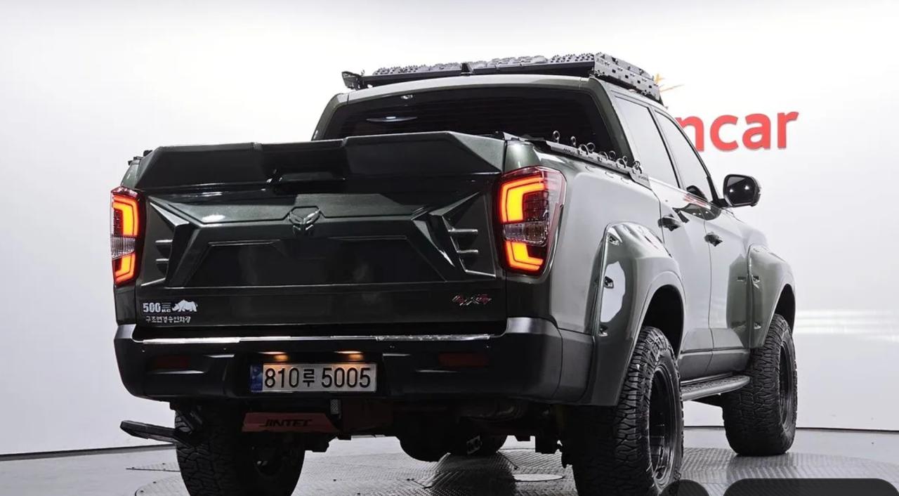KGM SsangYong Sports Khan 2022 года, вид сзади на площадке продавца: тёмно-зелёный кузов, внедорожная резина, корейский номер 810루5005